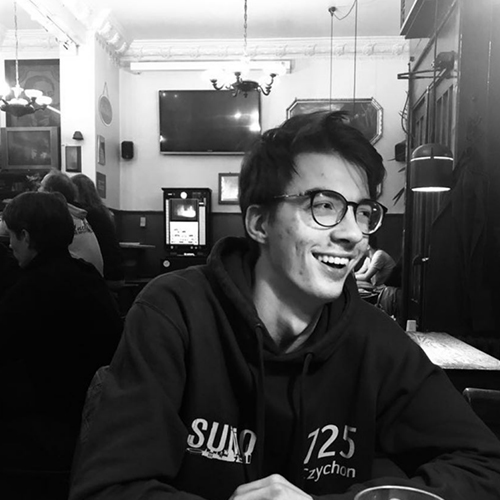 black and white photo with restaurant of young man with glasses and black hoodie