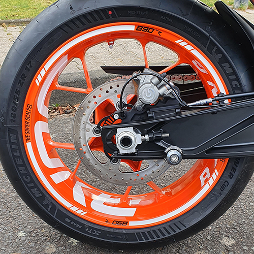 orange rim of motorcycle with decor on asphalt