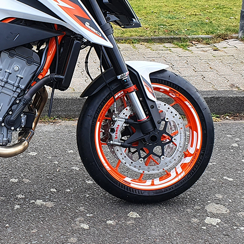 orange rim of motorcycle with decor on asphalt